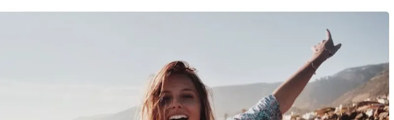 Femme les bras levés au bord de la mer