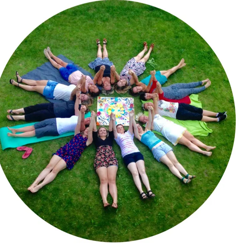 Groupe allongé en cercle dans l'herbe lors d'un atelier